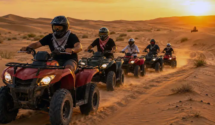 A line of riders wearing helmets steering quad bikes through rolling sand dunes in the Abu Dhabi desert during a golden sunset.