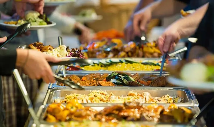 Close-up of guests serving food at a buffet spread during a desert safari camp dinner in Abu Dhabi.
