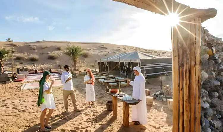 Guests enjoying Arabic coffee and dates at a desert camp in Abu Dhabi, dressed in traditional Arabic costumes for a photo session.