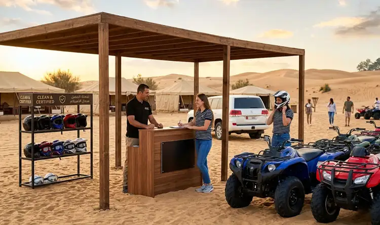 Guests completing their registration at a wooden desert camp desk while receiving safety helmets and goggles for a private quad bike tour Abu Dhabi experience.